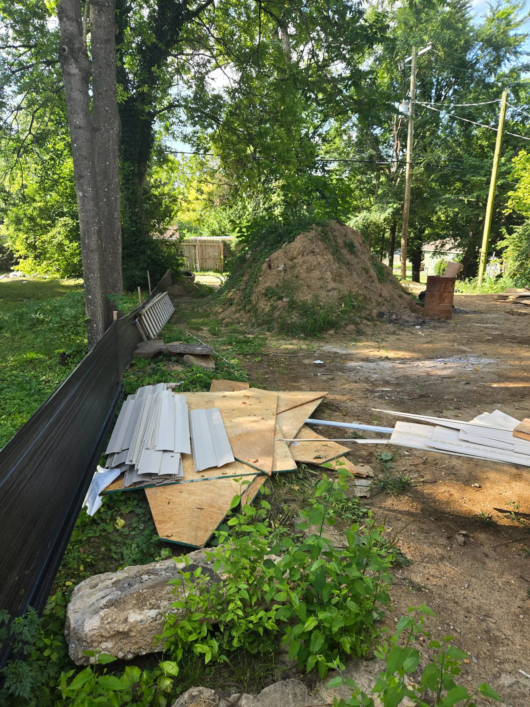 Cleared teardown site in East Tennessee with siding and plywood stacked for haul off
