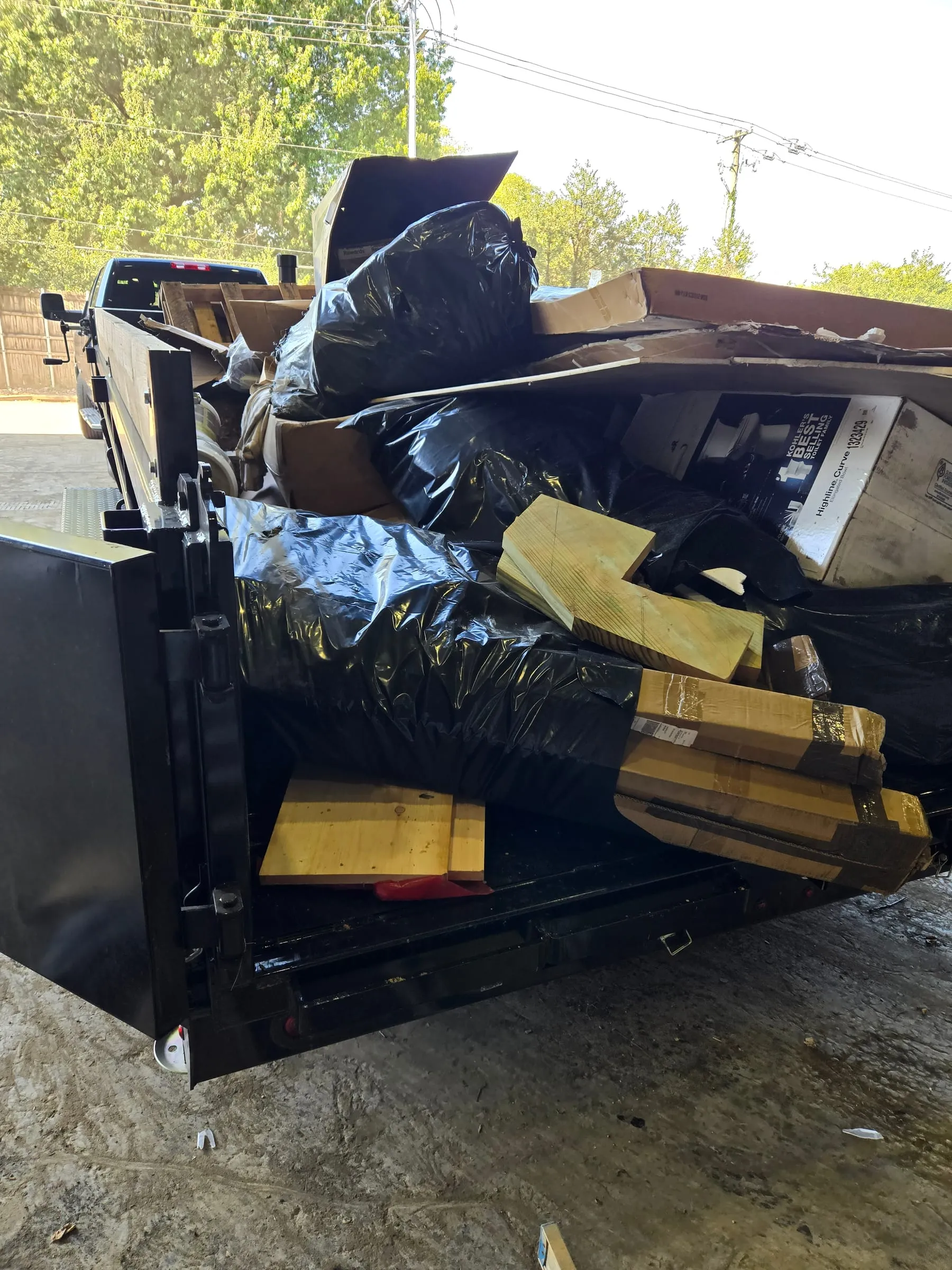 Dump trailer loaded with boxes, bagged trash, and old lumber from a Maryville cleanout