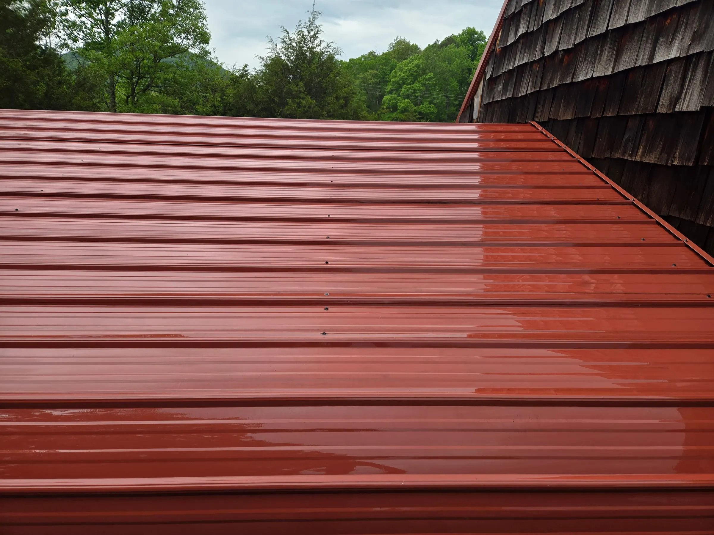 The same red metal roof rinsed clean with the original paint color showing edge to edge