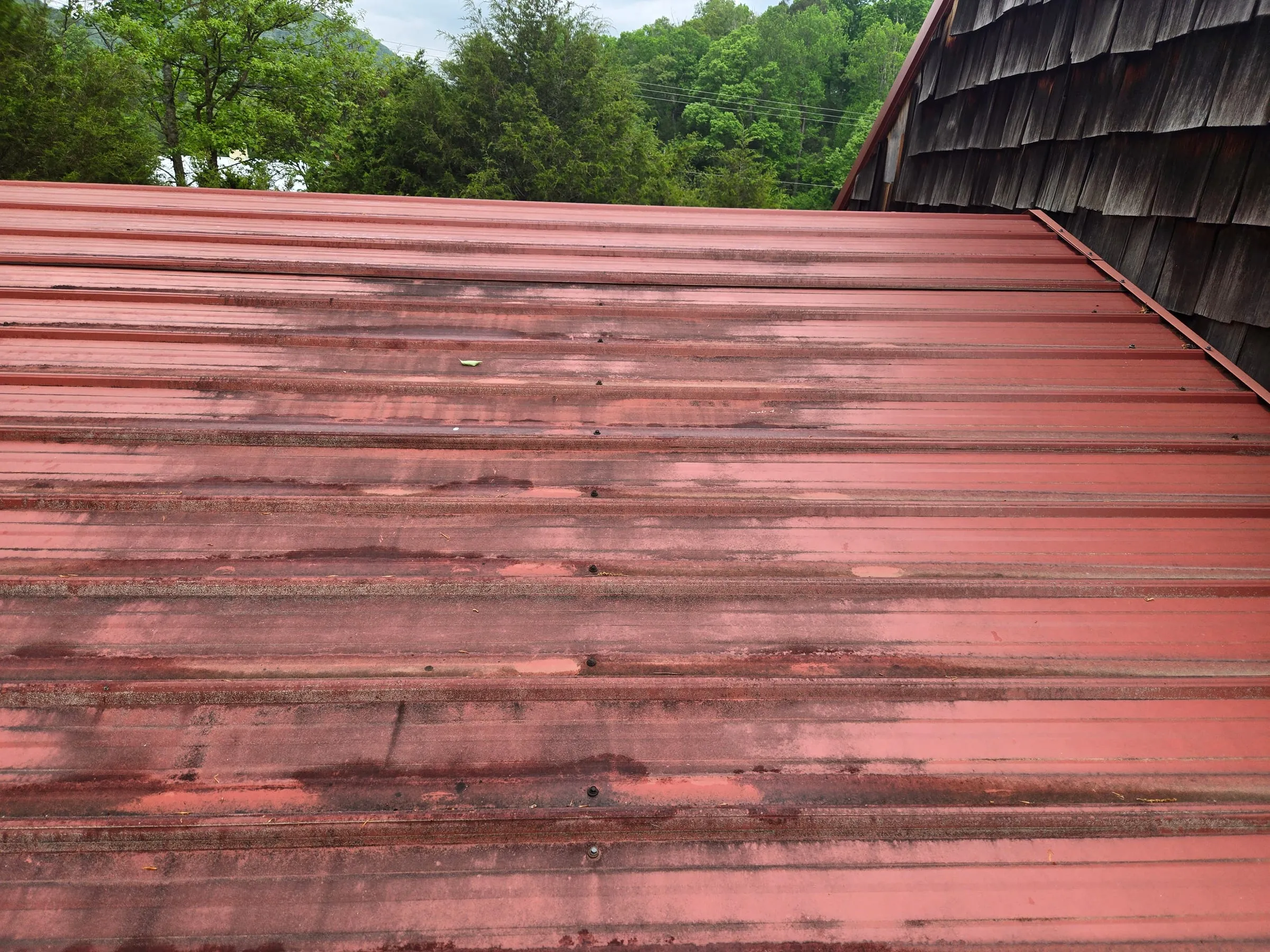 Red metal roof streaked with algae and grime before an East Tennessee wash